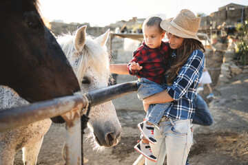 Mother with little son having fun a horse at farm ranch - Focus on kid face