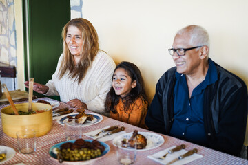 Happy latin grandparents having fun eating with her granddaughter at home - Focus on grandmother...