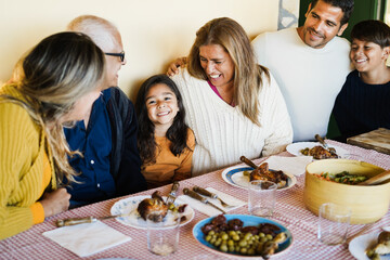 Happy latin family having fun eating together at home- Focus on girl face