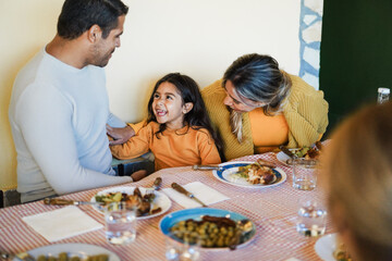 Fototapeta premium Latin parents having fun with their daughter during home dinner - Focus on girl face