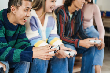 Obraz premium Multiracial young friends having fun playing video games at home - Focus on asian boy hand
