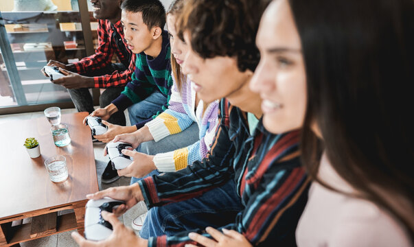 Multiracial young friends having fun playing video games at home - Focus on asian boy face