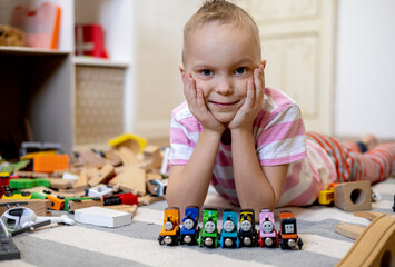 Children lie on the floor in a room with toys. Wooden train. Educational games for young children.