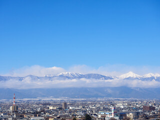 1月（冬）、高台から望む松本の街並みと、雲がかかった北アルプス 長野県松本市