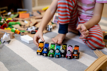 Kids play with wooden railway. Child with toy train. Cute kid playing cars and engine. Educational toys young children.