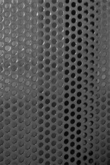 evocative black and white image of iron surface texture with cylindrical holes 