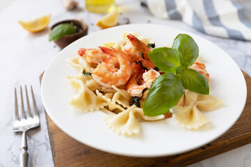 Mediterranean cuisine, seafood diet. Italian farfalle pasta with prawns garlic, basil and lemon on a marble tabletop.