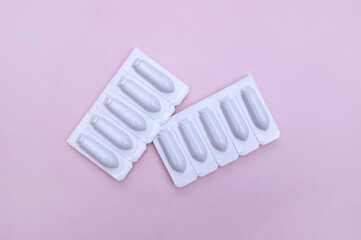 Gynecological medicines for women's health in form of suppository, capsules on pink background.