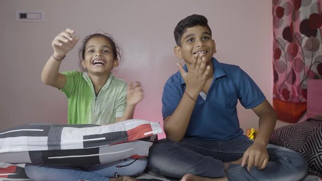 Happy Kids enjoying watching fun cartoon movies on television at home - concept of weekend or holiday entertinment and TV addication, waste of time and leisure activities.