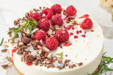 Cheesecake with raspberries, chocolate, hazelnuts and rosemary leaves on kitchen coutertop