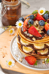 Pancakes with chocolate paste and hazelnuts, banana, strawberry and blueberry