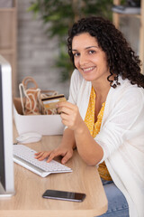 young woman holding credit card and using computer