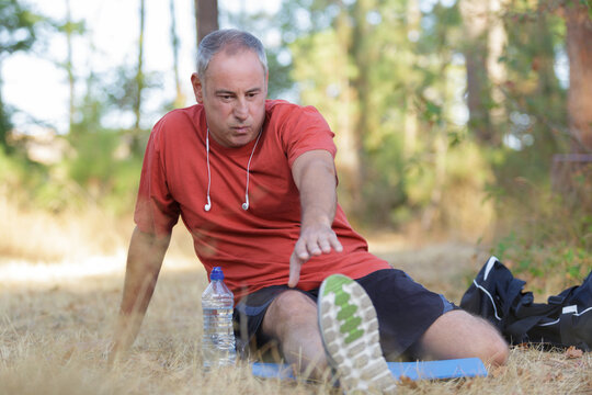 male runner stretching outdoors in the forest
