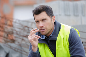 happy builder smoking cigarette on construction site