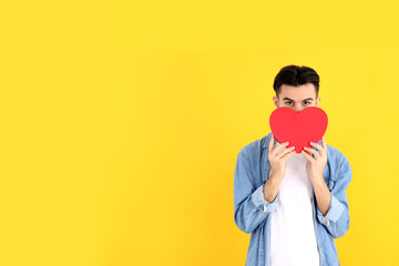 Fototapeta Attractive guy with heart on yellow background obraz
