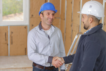 Men shaking hands on indoor building site