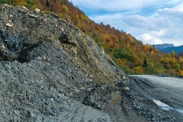 Collapse of rock, sand on the serpentine road on a sunny autumn day