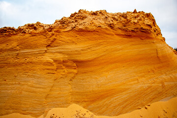 Textural sand, with  relief surface, multi-colored layers and different in size of granules, in outdoor sand career, after mining ore and sand for construction.