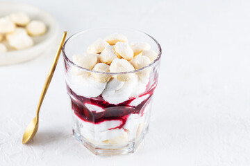 Homemade dessert with aquafaba meringue, coconut cream and cherry in a glass. Sugar, lactose free, vegan.