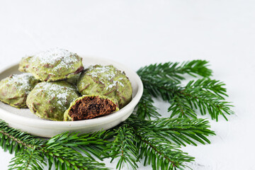 Chocolate gingerbreads with matches in mint glaze in a plate with fir branches. Sugar, gluten and lactose free and vegan.