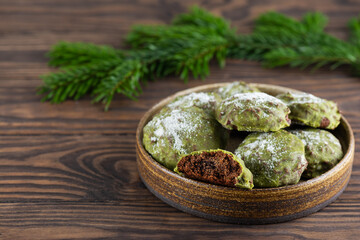 Homemade mint gingerbread cookies with matcha and fir branches on a wooden table. Sugar, gluten and lactose free and vegan.