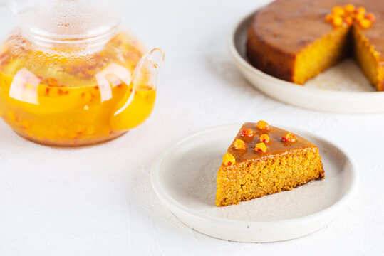 A piece of homemade vegan sea buckthorn pie, mannik with orange and tea in a teapot. Sugar, gluten and lactose free.