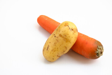 A potato lays on a carrot on a white background.