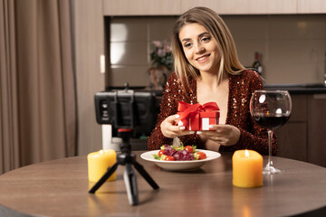 date online. women at home at the table and making a video zoom call using the application on the smartphone. Opens a gift online. concept of remote celebration of anniversary or valentine's day
