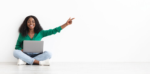Smiling black woman with laptop showing empty space