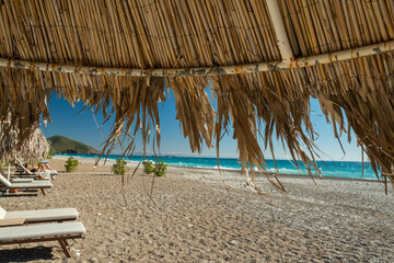 Fototapeta na wymiar Cozy sun loungers and palm parasols on a beautiful beach. 