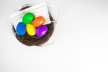 Easter eggs colorful painted in bird nest with protective Face mask top view, Happy Easter Holiday,medical health, Covid-19, coronavirus concept copy space isolated on white background