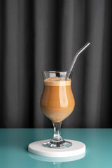 Coffee with cream in a glass. Gray fabric background.