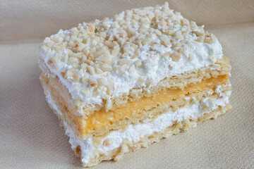 Millefeuille in crunchy overlapping layers made with puff pastry and filled with pastry cream and meringue topped with toasted chopped almonds and icing sugar. Traditional Spanish sweets and desserts.