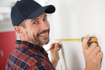 happy man measures on the wall with a ruler