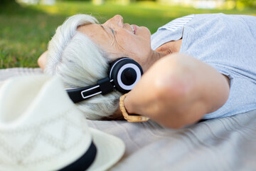 smiling elder lady listening to music on the park