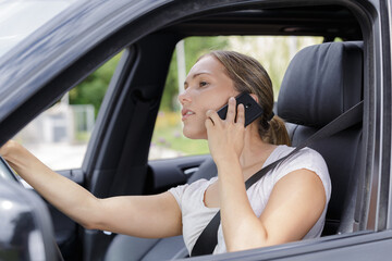 Fototapeta na wymiar woman using mobile phone while driving her car