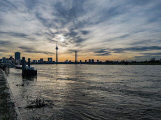 Düsseldorf, Germany, 1 January 2022. Dramatic sky at dusk over the skyline of Düsseldorf with its landmark Rheinturm TV tower and the Rhine River in the foreground.