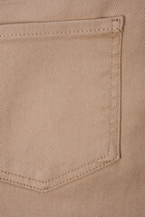 Close-up shot of beige denim texture with stitching.