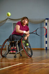 young woman on wheelchair playing tennis on tennis court
