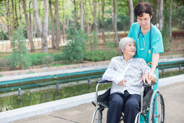 Asian healthcare worker drive a wheelchair of old patient, happy hospital, rehabilitation activity, elderly health care