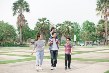 Asian children and parent relax in public garden, they holding hand and walk in family time, family happiness activity