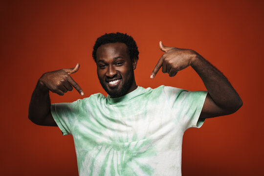 Young black man with beard smiling and pointing fingers at himself