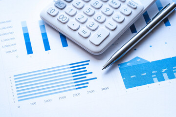 Calculator, steel pen, and financial data with graphs. The calculator and the financial report, analysis report concept