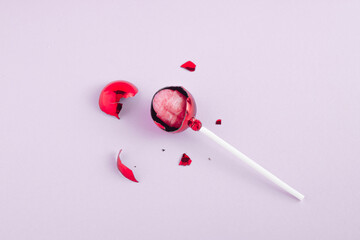 Concept of broken red christmas bauble with pink lollipop in the bauble. Holiday  sweet idea.