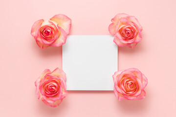 Blank sheet paper with pink roses on pink background with copy space for design or text. Top view with blank card and flower