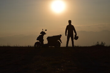 silhouette of a scooter and a man on a sunset