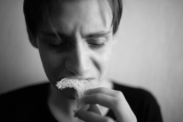 Thin and emaciated young man eating bread