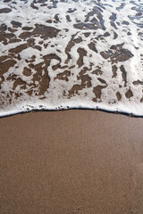 Smooth sandy at the beach and beautiful wave in background. Soft wave blue ocen and sandy beach. Small waves lapped the beach