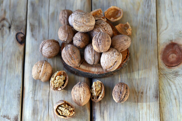 Walnuts in shells on a wooden surface.