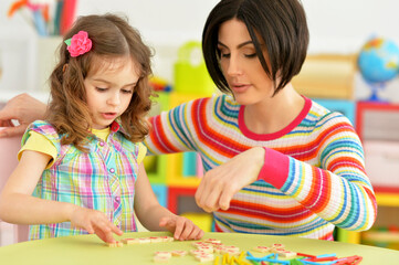Portrait of cute little girl with her mother studying